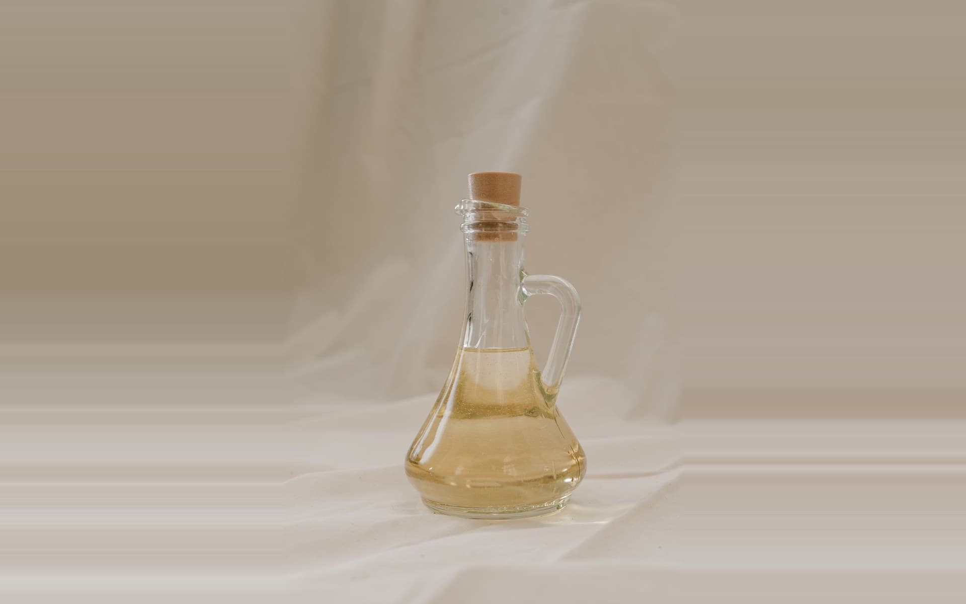 Cold-pressed macadamia oil being poured from a glass bottle